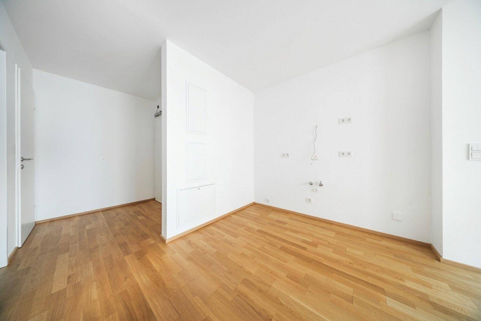 Unmöblierter Raum mit Parkettboden und Wandanschlüssen, bereit für die Einrichtung.