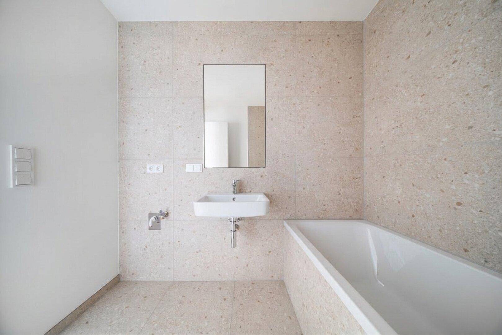 Modernes Badezimmer mit beigefarbenen Fliesen, Badewanne und einem einzelnen Waschbecken.