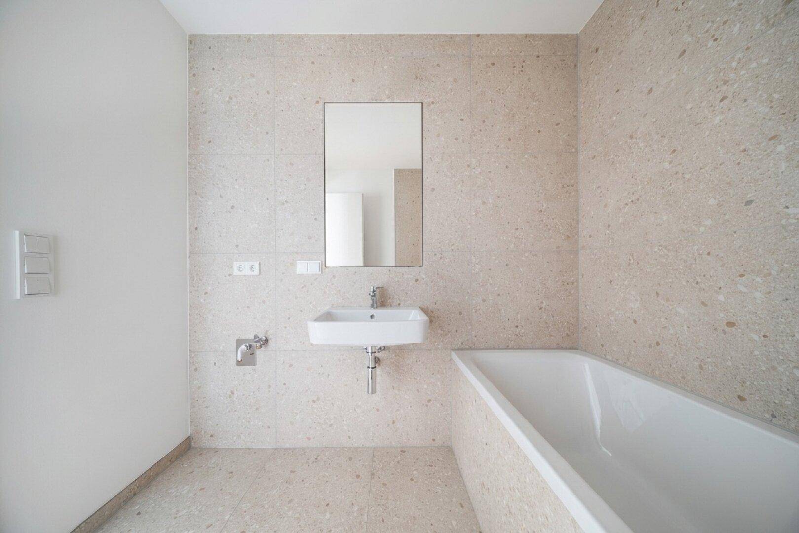 Modernes Badezimmer mit hellen Fliesen, Einzelwaschbecken und integrierter Badewanne.