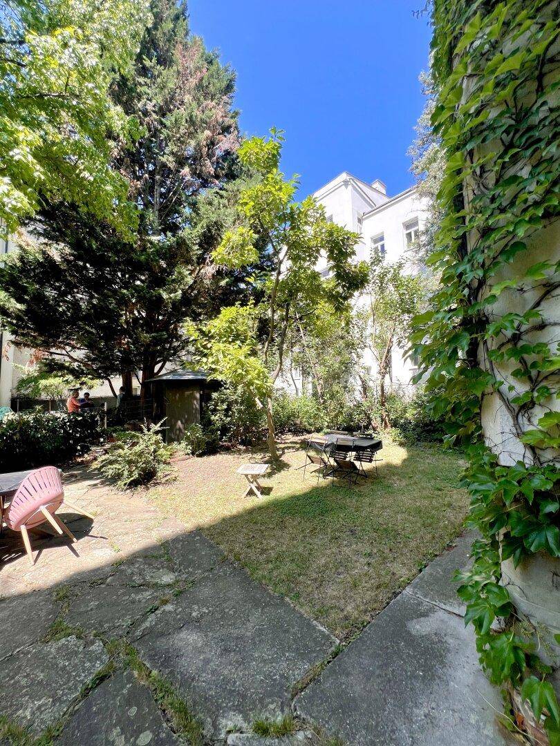 Ruhiger Gemeinschaftsgarten mit Rasenfläche, Bäumen und Sitzgelegenheiten, ideal zum Entspannen.