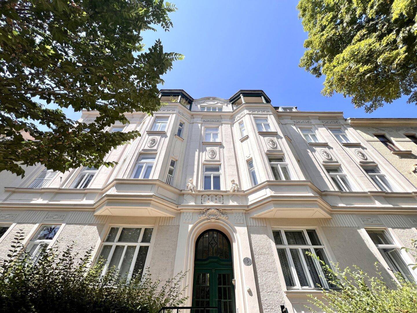 Elegante Fassade eines Altbaus mit reich verzierten Details und grüner Eingangstür.