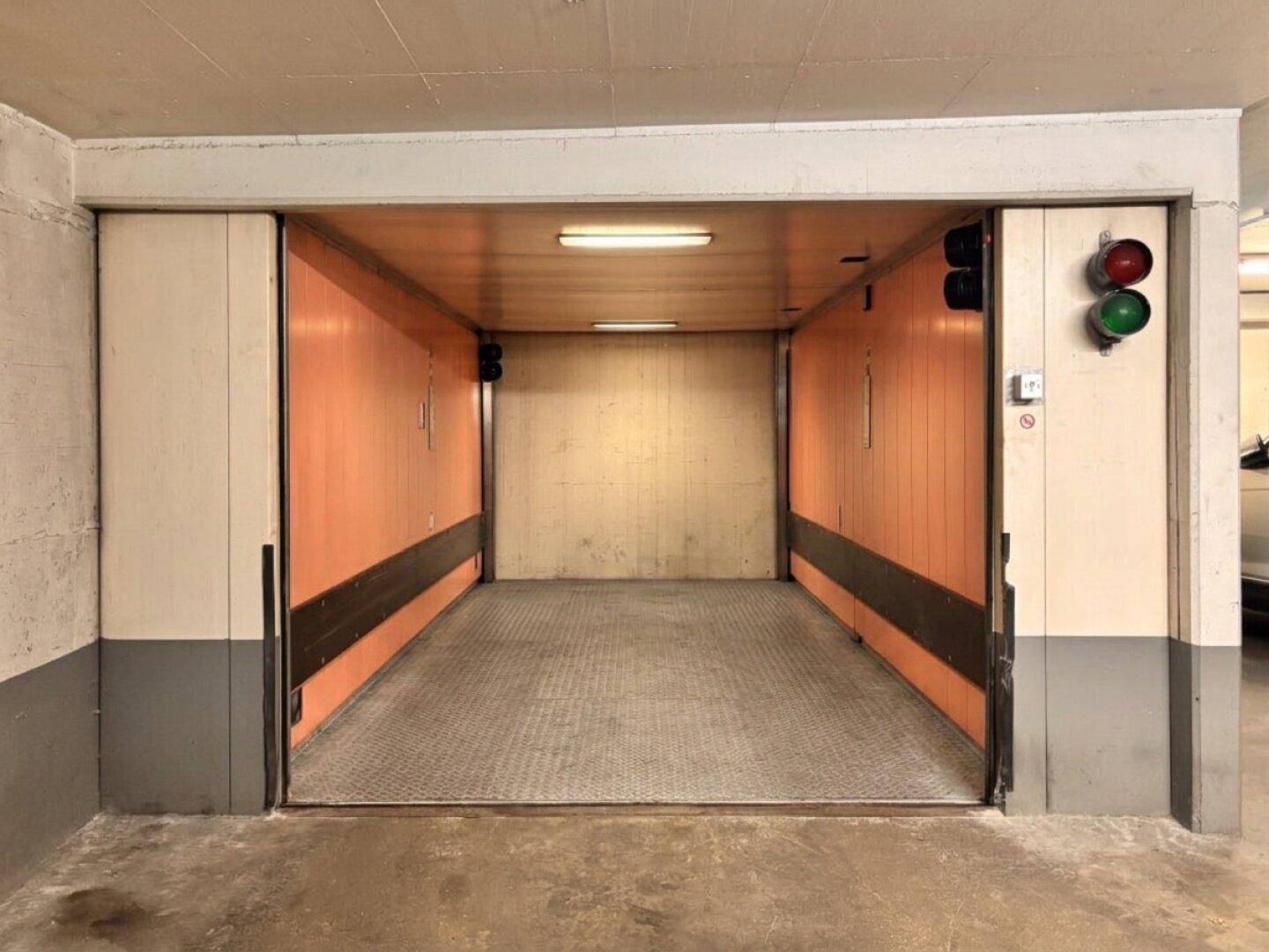 Geräumiger Autoaufzug in einer Tiefgarage mit orangefarbenen Seitenwänden.