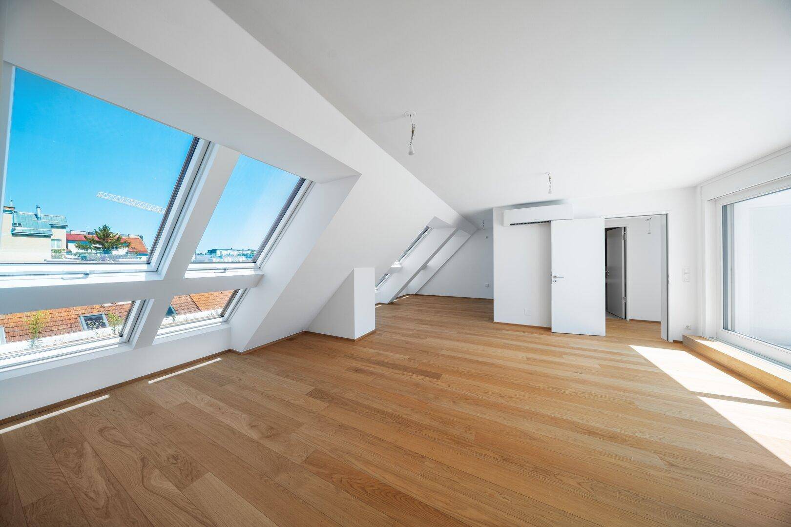 Helles Dachgeschosszimmer mit großen Dachfenstern und neuem Holzparkettboden.