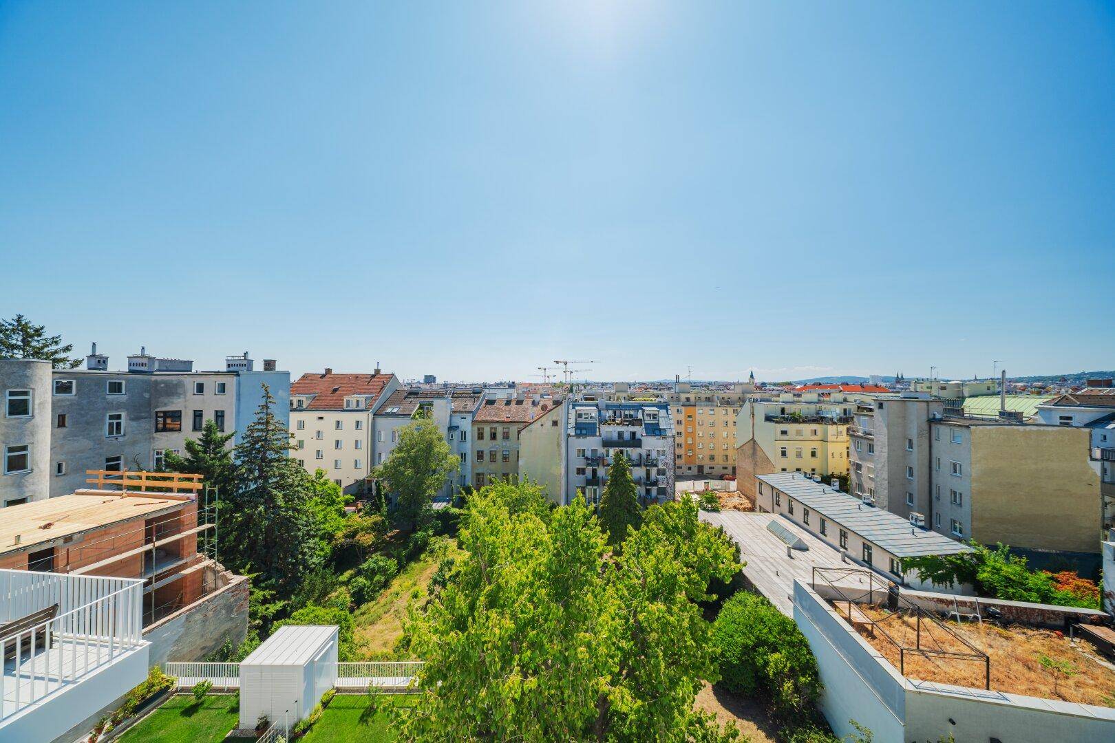 Panoramablick über die Stadt mit grünen Bäumen und umliegenden Wohngebäuden an einem sonnigen Tag.
