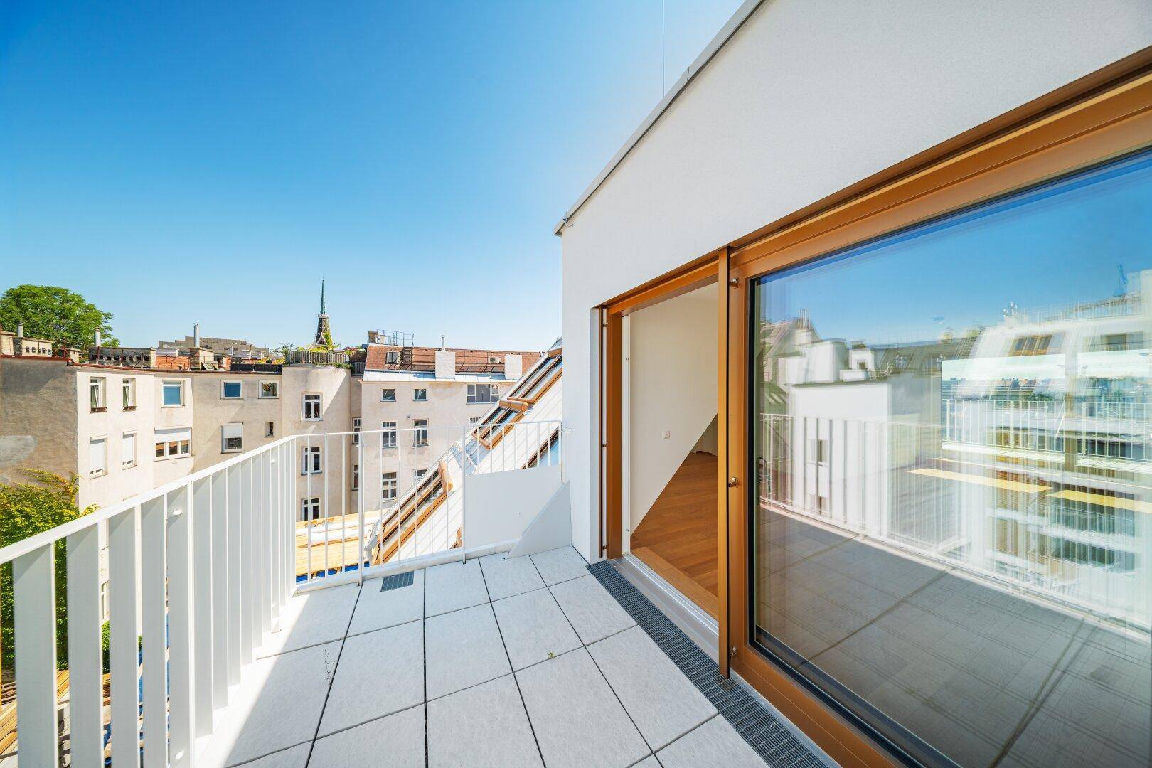 Helle Dachterrasse mit Fliesenboden und weitem Blick über die städtische Umgebung.