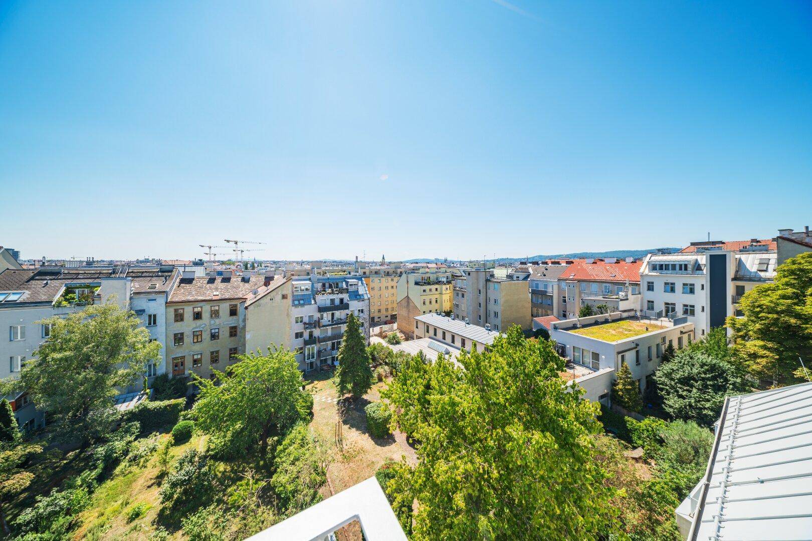 Weitläufiger Blick vom Balkon über die Stadt und die grünen Hügel am Horizont.