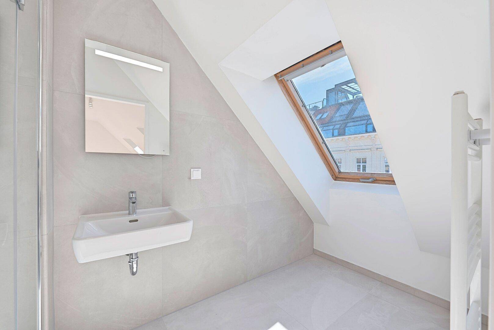Helles Badezimmer mit Dachfenster, modernem Waschbecken und beheiztem Handtuchhalter.
