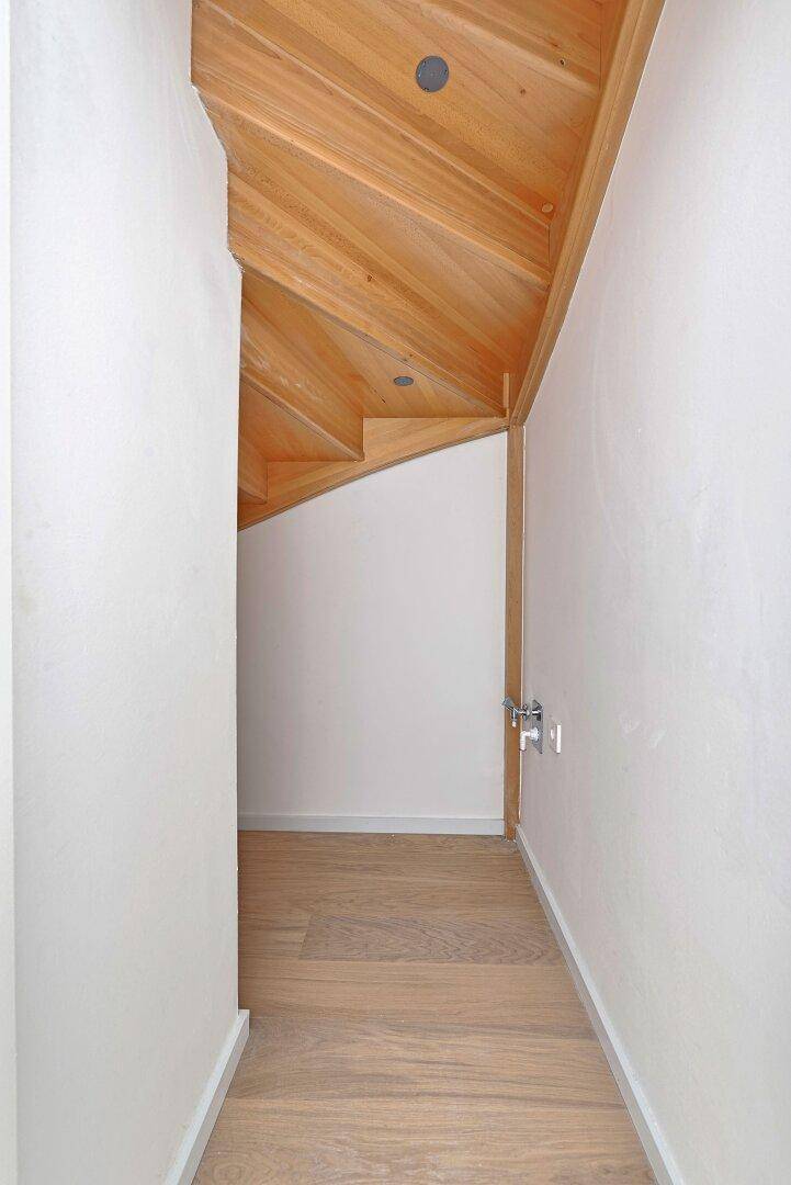 Schmaler Abstellraum mit schräger Holzdecke und hellem Holzfußboden.