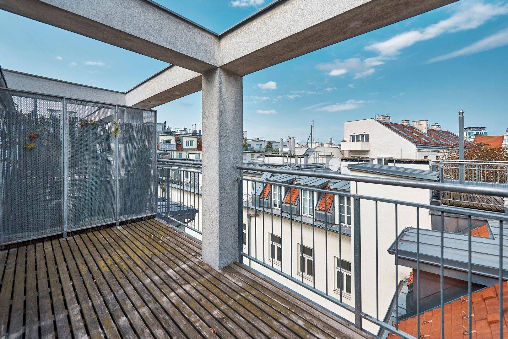 Geräumige Dachterrasse mit Holzbelag und Metallgeländer bietet einen weiten Stadtblick.