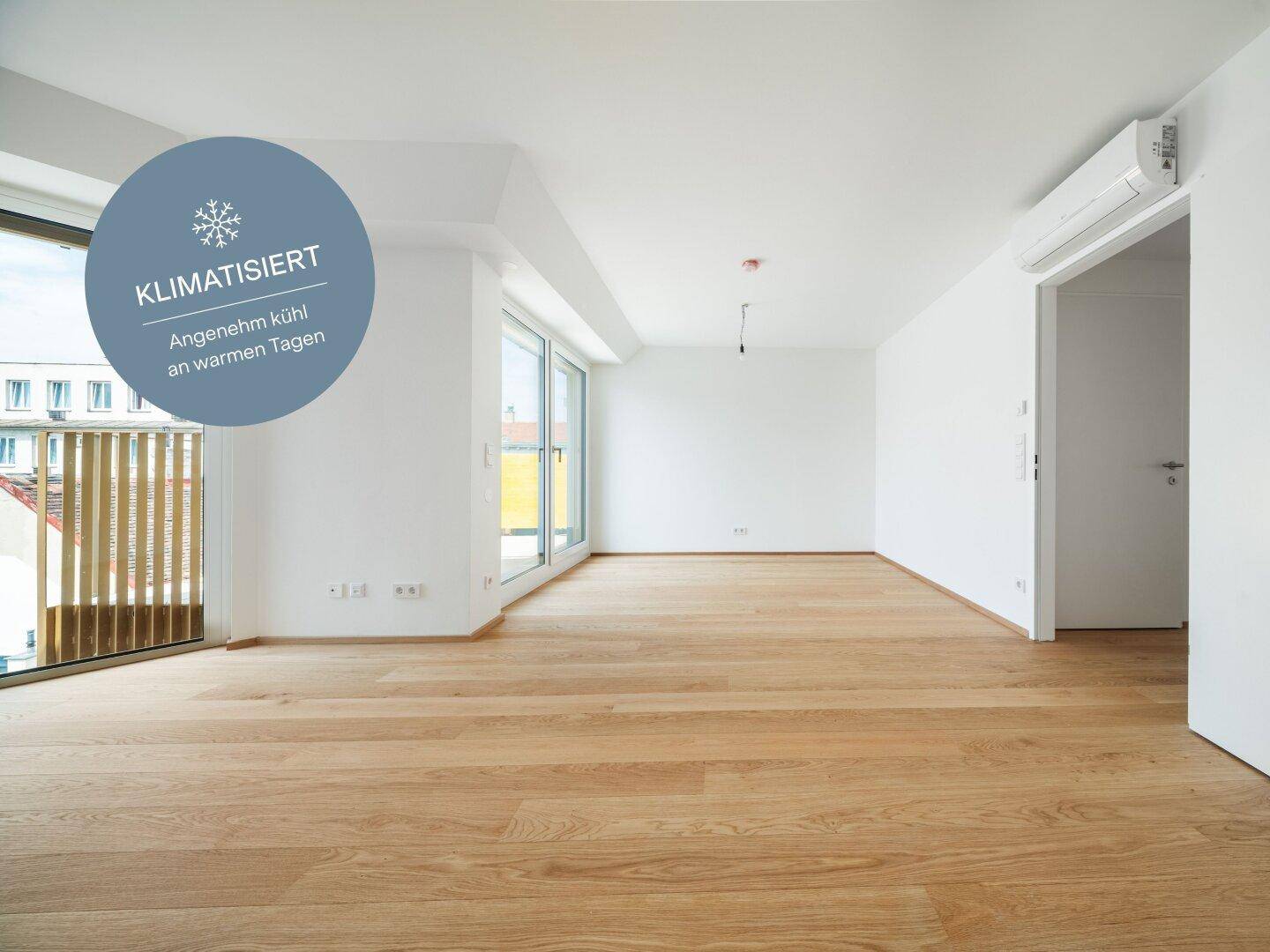 Heller, leerer Raum mit hochwertigem Holzboden, großen Fenstern und Klimaanlage, ideal für modernes Wohnen.