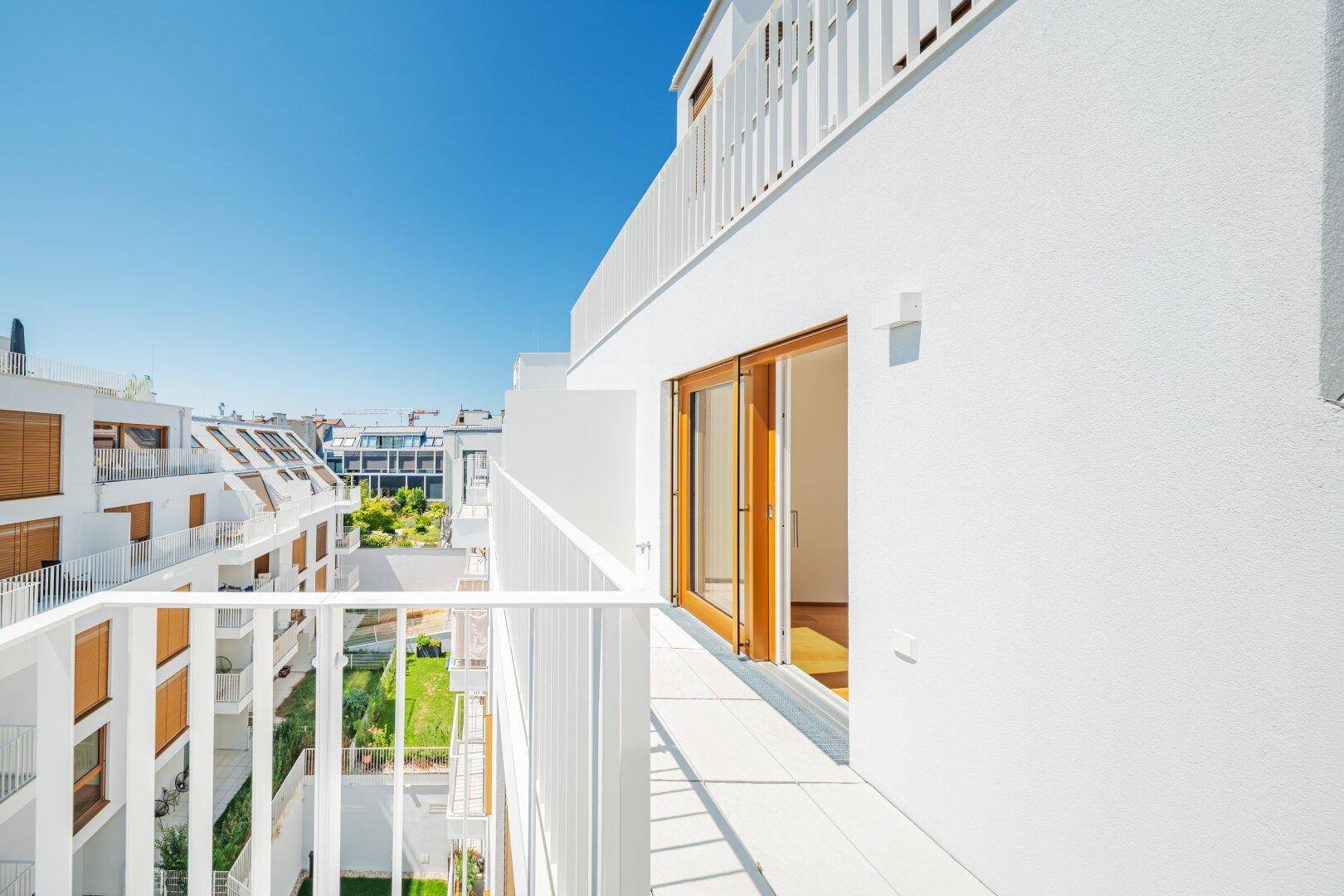 Heller Balkon mit Zugang zum Innenraum und Blick auf die Nachbarschaft.