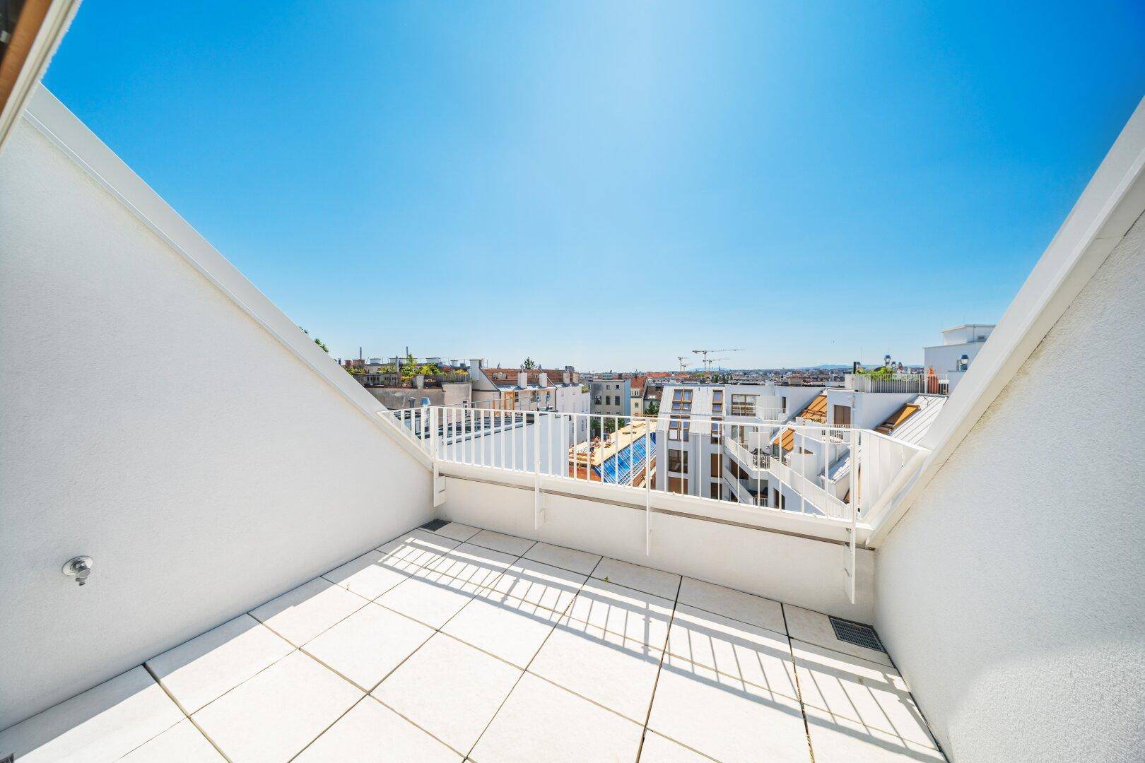 Geräumige Dachterrasse mit Fliesenboden und weitem Blick über die Stadt.