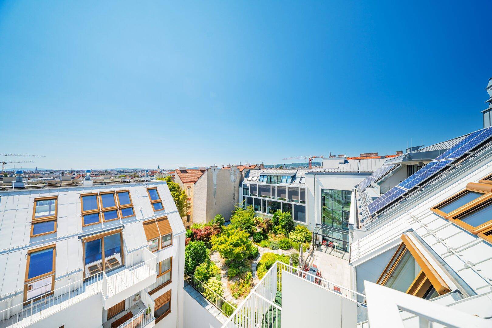 Luftaufnahme eines modernen Wohnkomplexes mit begrüntem Innenhof und Solaranlagen.