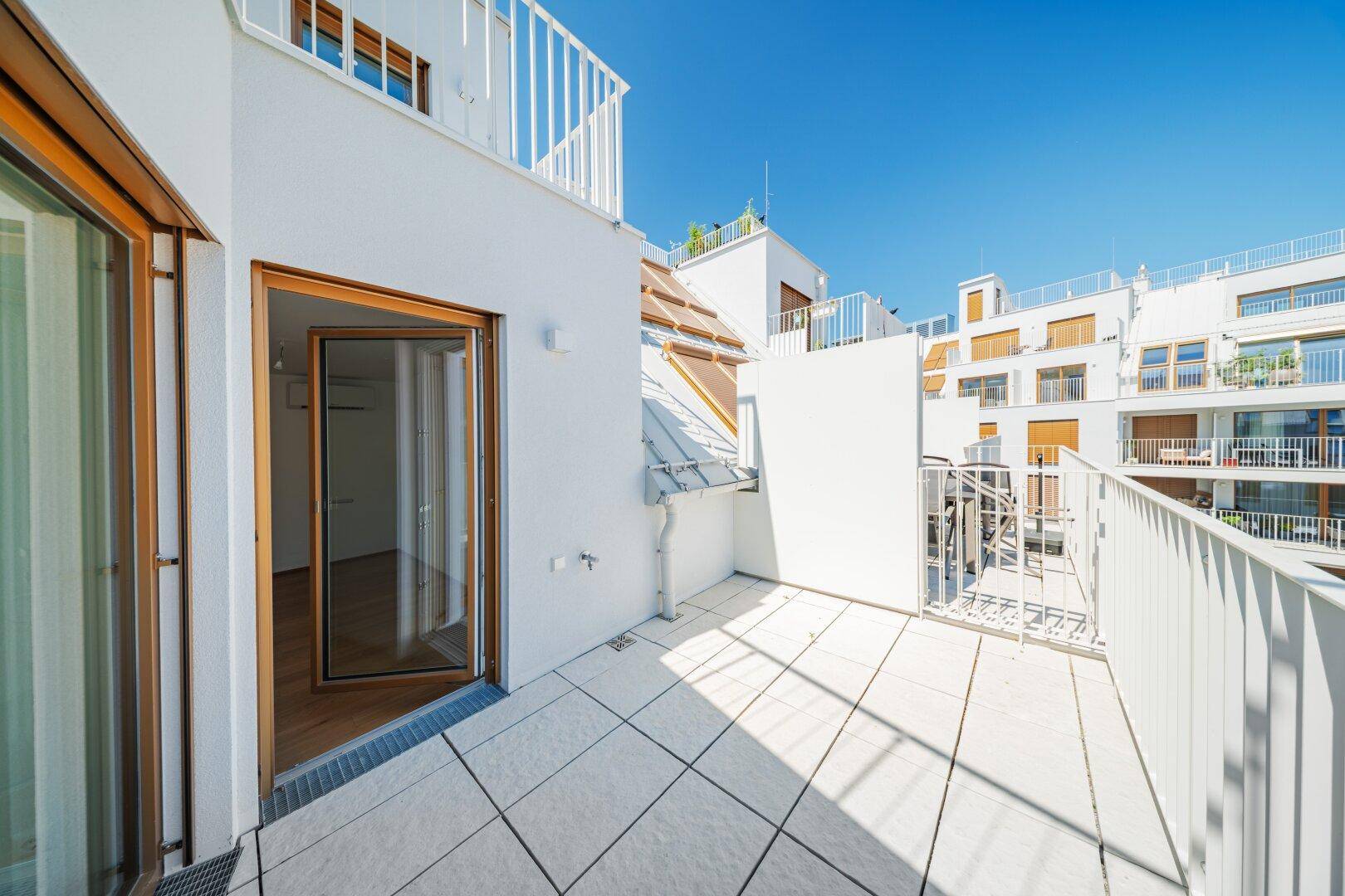 Kleiner Balkon mit Fliesenboden und Zugang zu einem hellen Innenraum des Gebäudes.