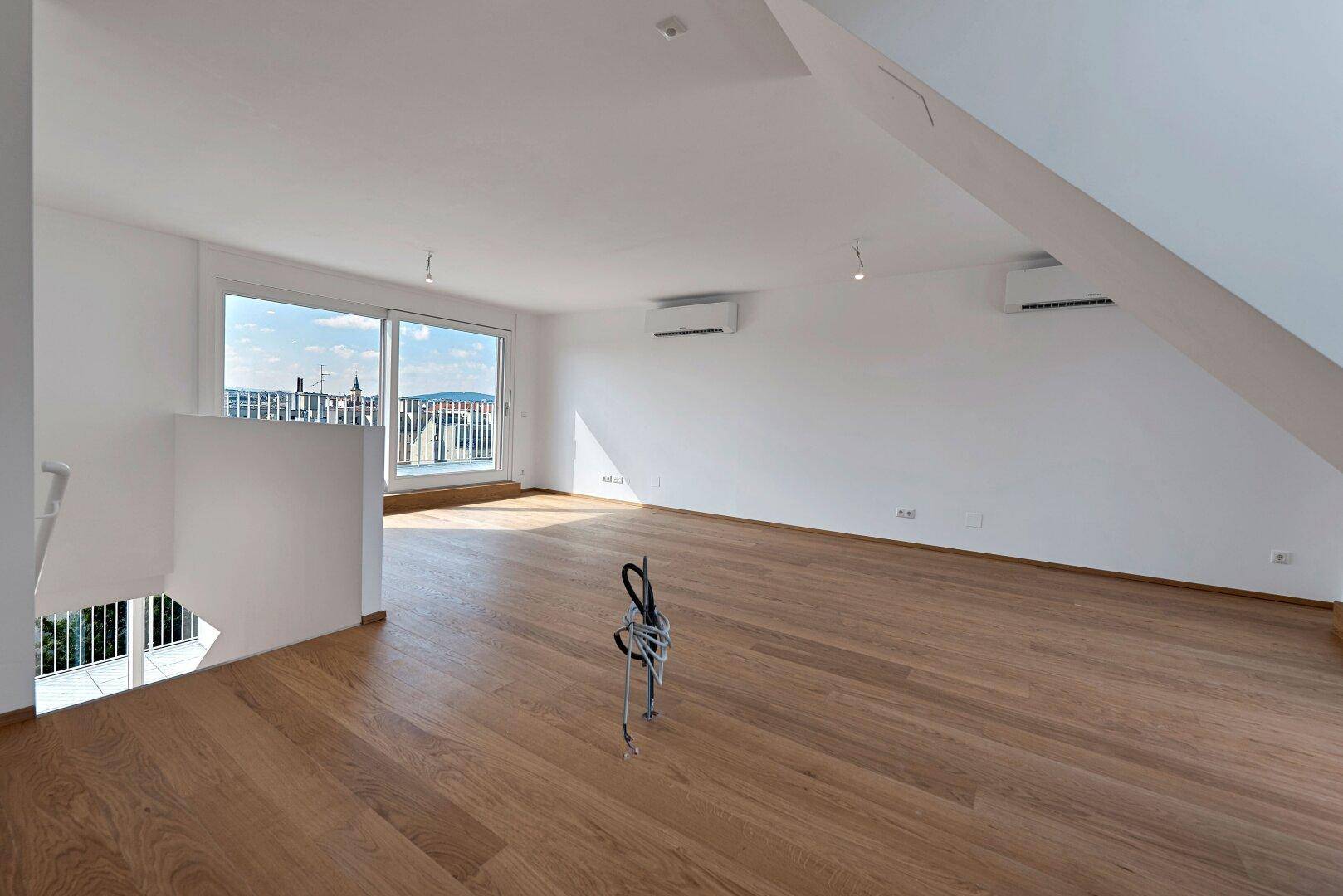 Großzügiger Dachgeschossraum mit Holzboden, zwei Klimaanlagen und Terrassenzugang.