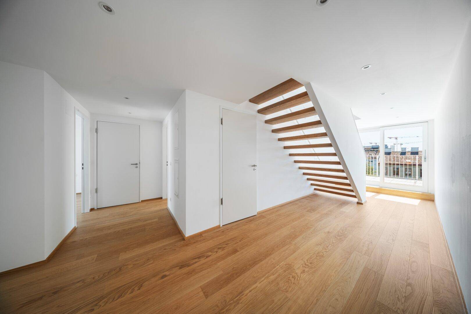 Heller Flur mit Holztreppe und Zugang zu weiteren Räumen sowie zur Terrasse.