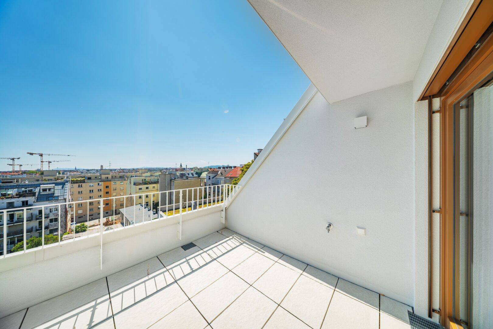 Sonniger Balkon mit Stadtblick und weißem Geländer, perfekt zum Entspannen im Freien.