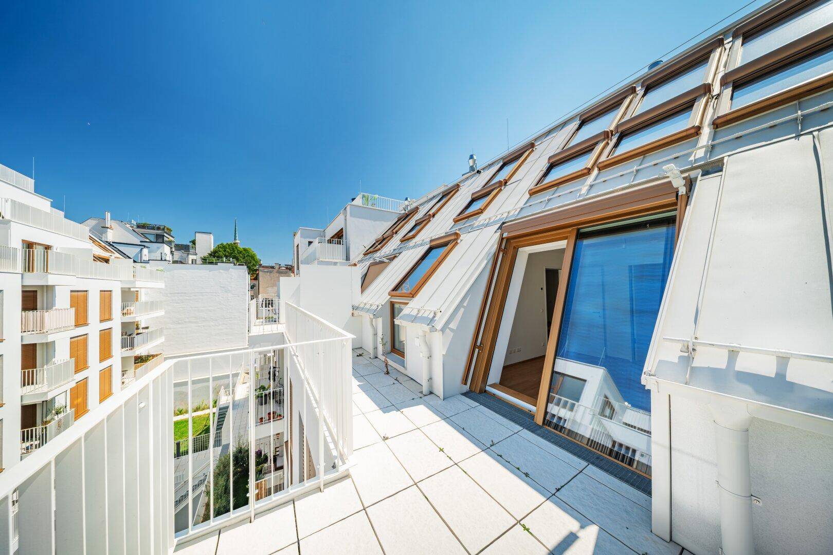 Dachterrasse mit Blick auf die moderne Architektur des Gebäudes und die vielen Dachfenster.