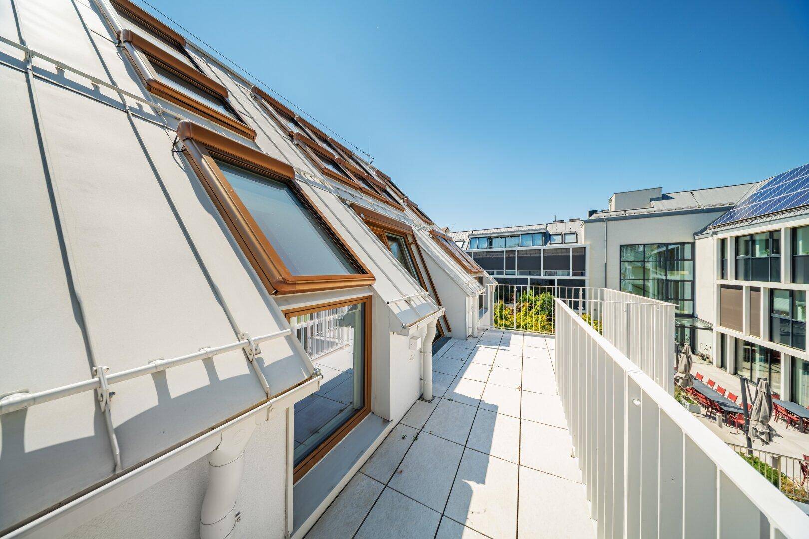 Dachterrasse mit Blick auf die umliegenden Gebäude, Dachfenster und Solaranlagen.