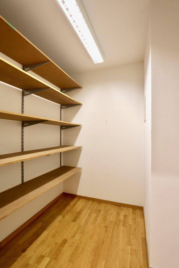 Praktischer Abstellraum mit mehreren Holzregalen und Parkettboden für zusätzlichen Stauraum.