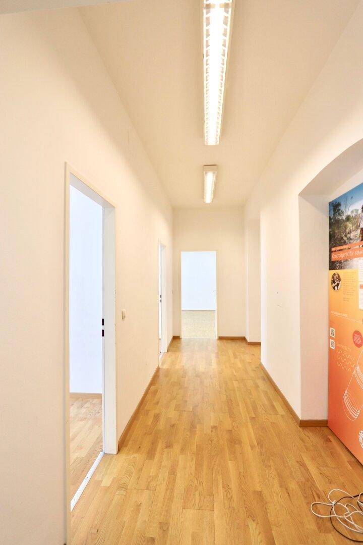 Langer, heller Flur mit Parkettboden und mehreren Türen, die zu den Büroräumen führen.