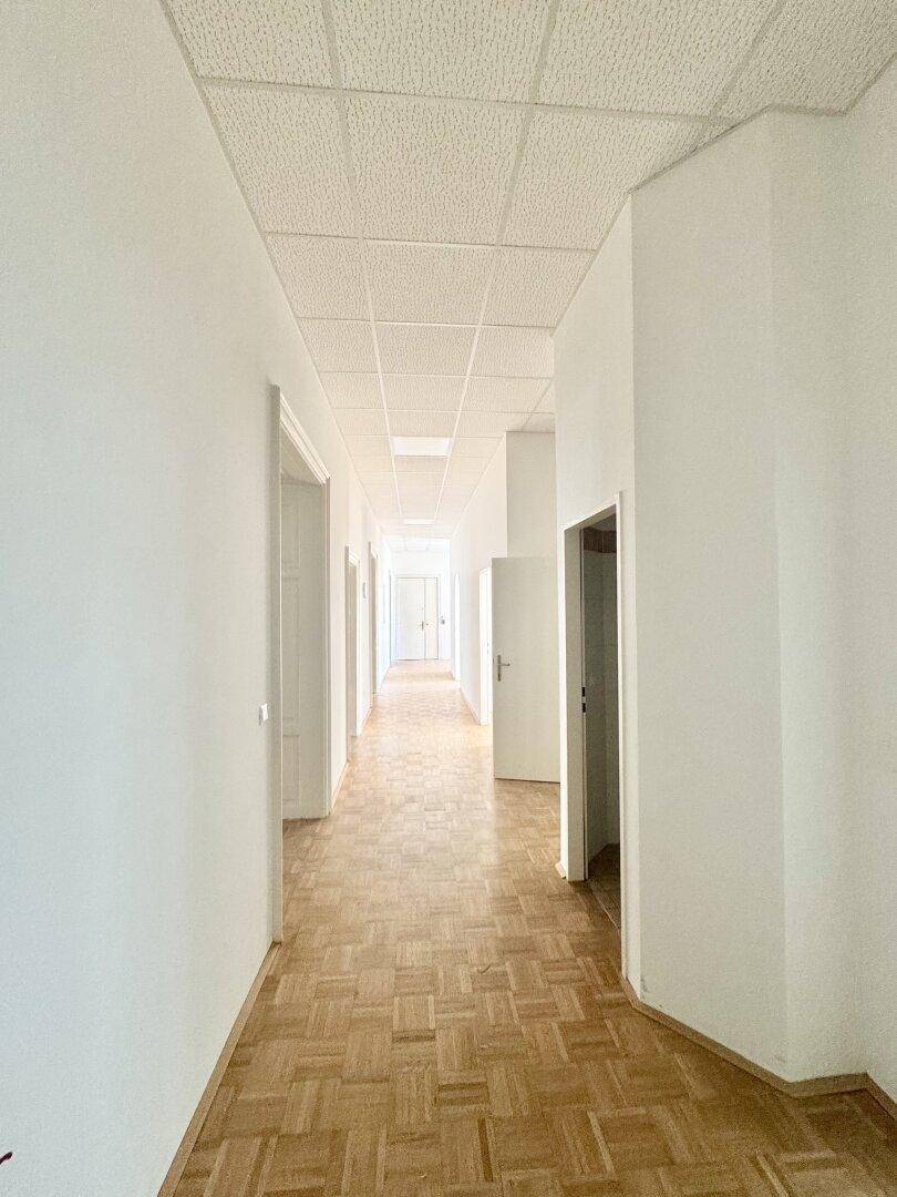 Langer Flur mit Parkettboden und mehreren Türen, der zu verschiedenen Räumen führt.