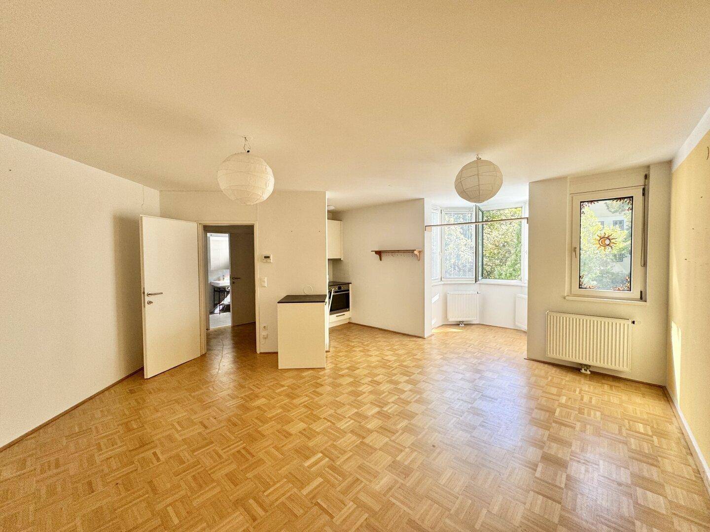 Geräumiger Wohnbereich mit Parkettboden und offener Küchenzeile, bereit zur individuellen Gestaltung.