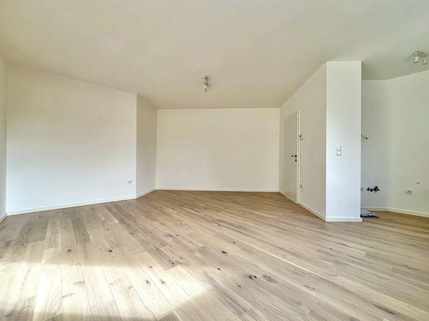Geräumiger, heller Raum mit hellem Holzparkett und weißen Wänden, bereit zum Einrichten.