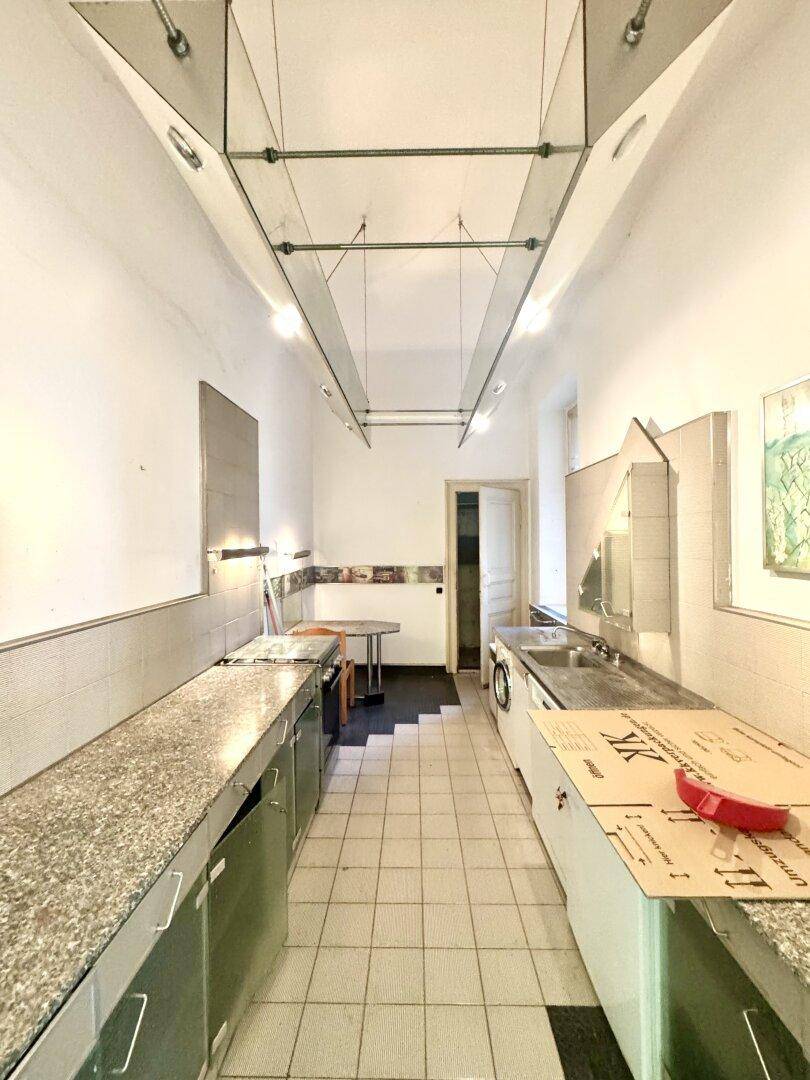 Lange, schmale Küche mit Fliesenboden und einfachen Einbauten, bereit für eine Modernisierung.