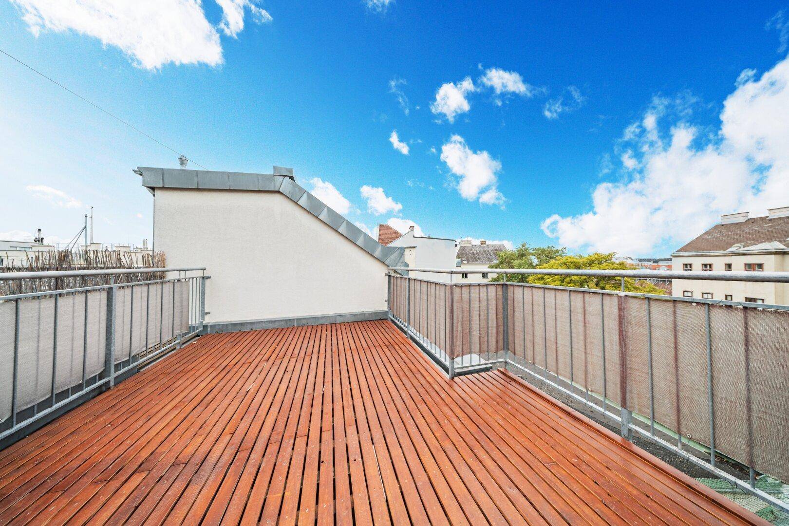 Weitläufige Dachterrasse mit Holzdielen und Metallgeländer, ideal für Entspannung im Freien.