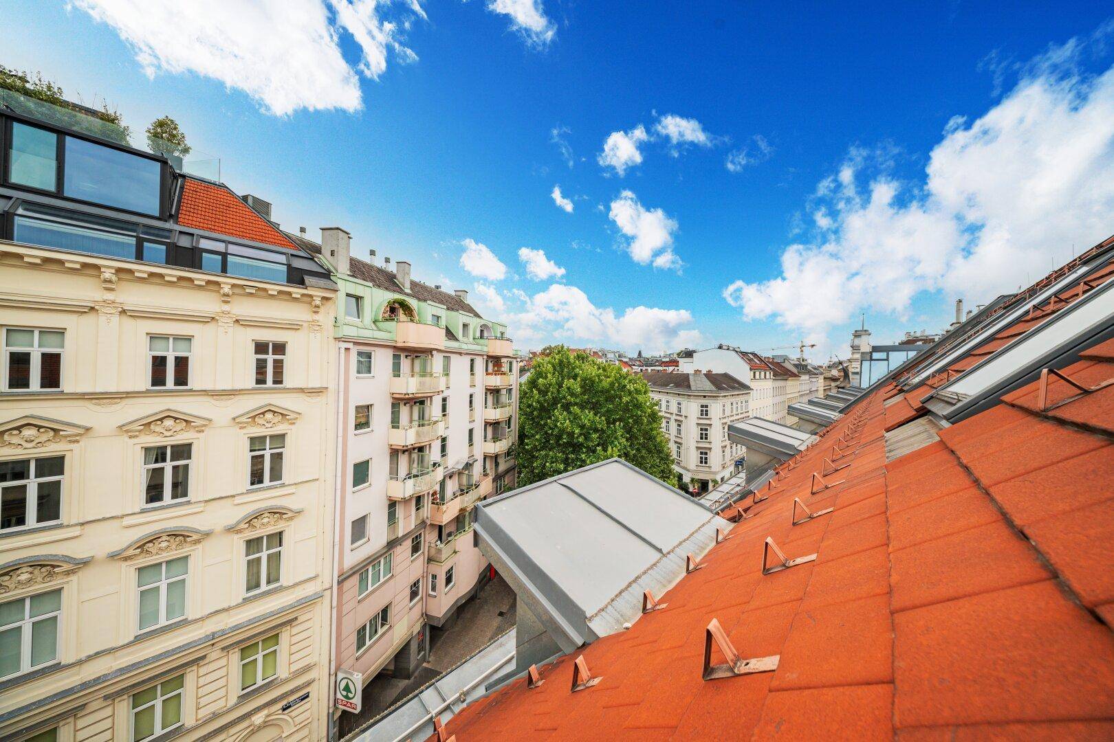 Panoramablick über die Dächer der Stadt mit historischen Gebäuden und blauem Himmel.