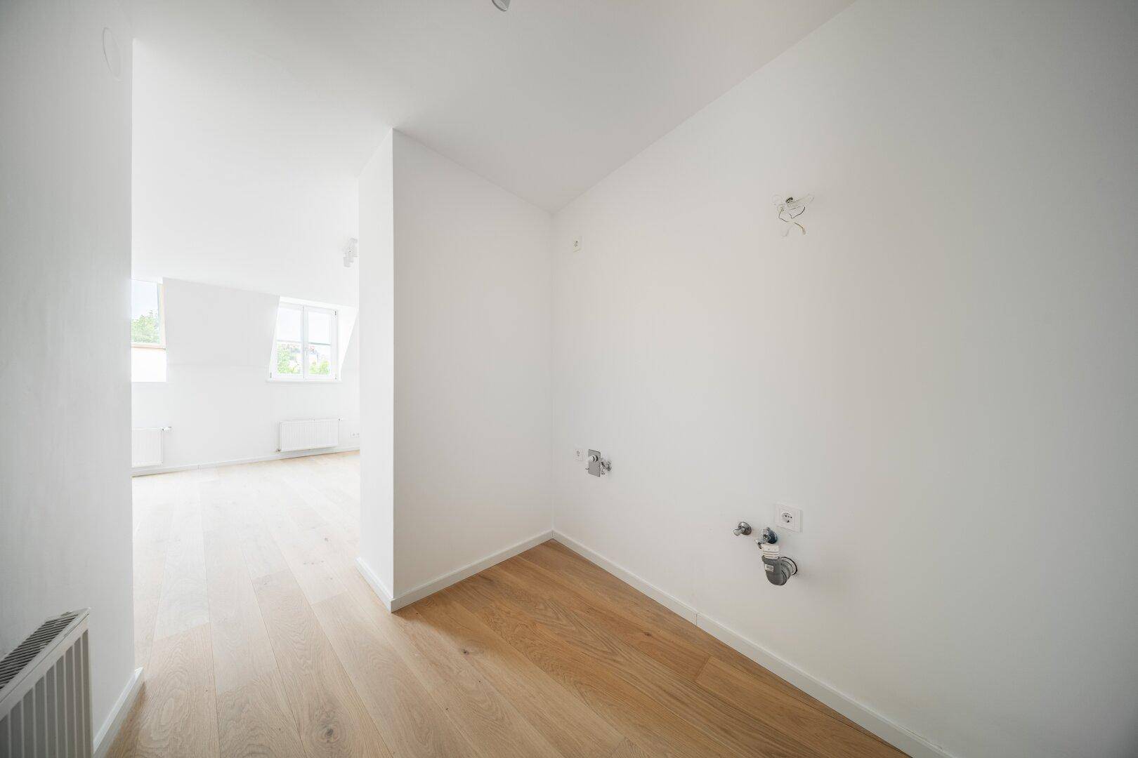 Heller Raum mit Holzboden und vorbereiteten Anschlüssen, ideal als Hauswirtschaftsraum.