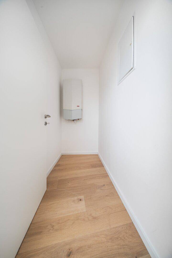 Praktischer Abstellraum mit Holzboden und Heizungsanlage, ideal für zusätzlichen Stauraum.