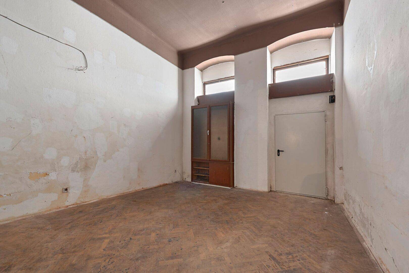 Großer, unrenovierter Raum mit hohen Fenstern und Fischgrätparkett, bereit für die Renovierung.