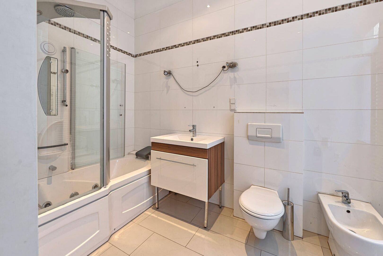 Modernes Badezimmer mit Duschwanne, Waschbecken, WC und Bidet.