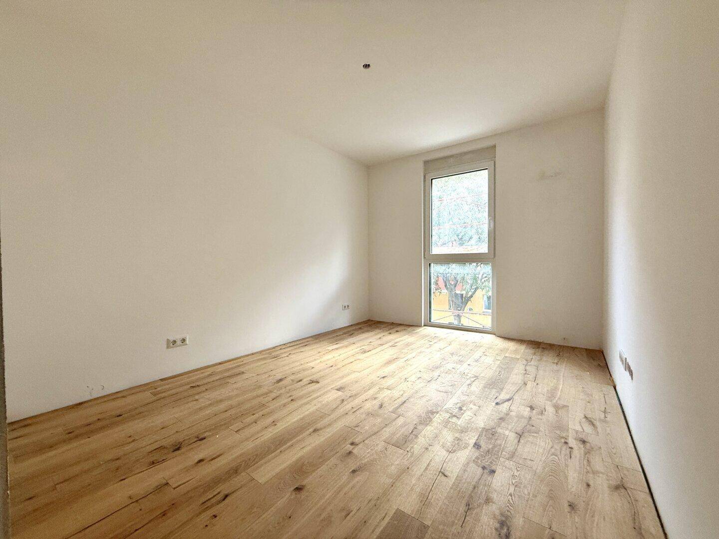Helles Schlafzimmer mit neuem Holzboden und großem Fenster für viel Tageslicht.