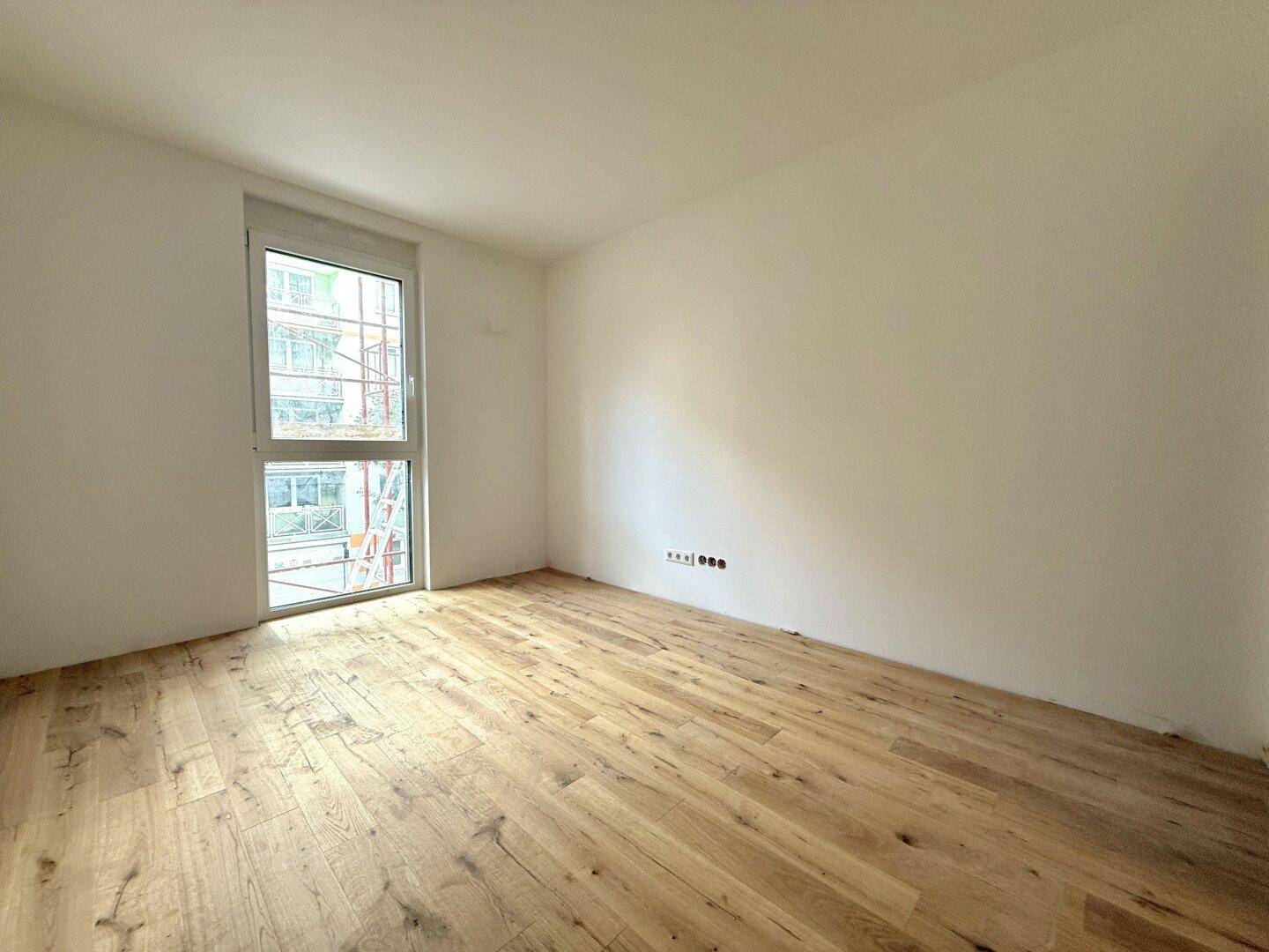 Helles Zimmer mit Echtholzdielenboden und großem Fenster, ideal als Schlaf- oder Arbeitszimmer.