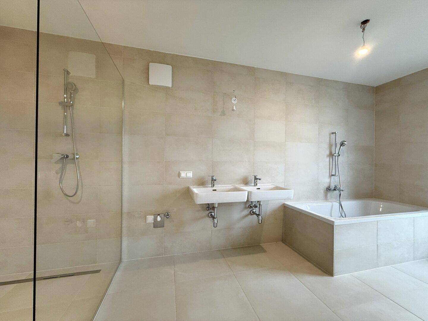 Geräumiges Badezimmer mit Fliesenboden, begehbarer Dusche, Badewanne und zwei Waschbecken.