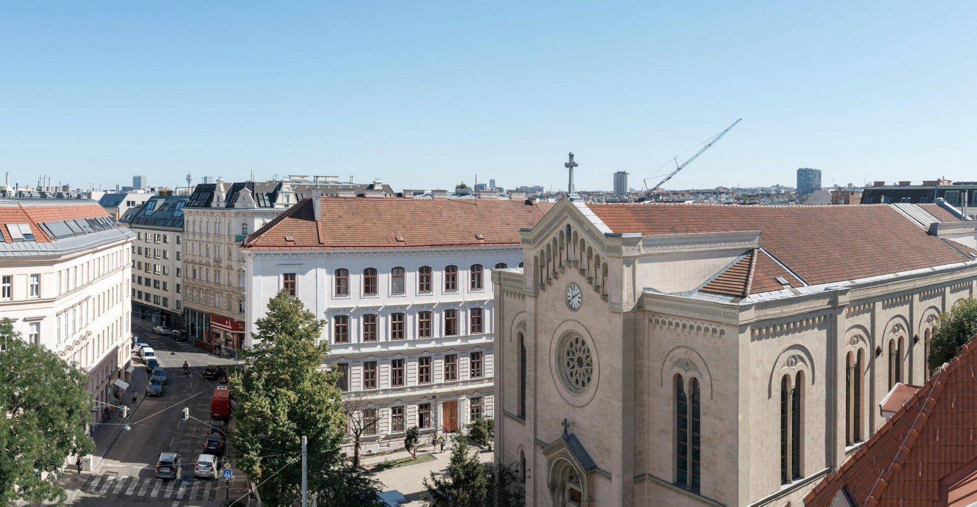 Blick über eine Stadtstraße mit historischen Gebäuden und einer Kirche unter klarem Himmel.
