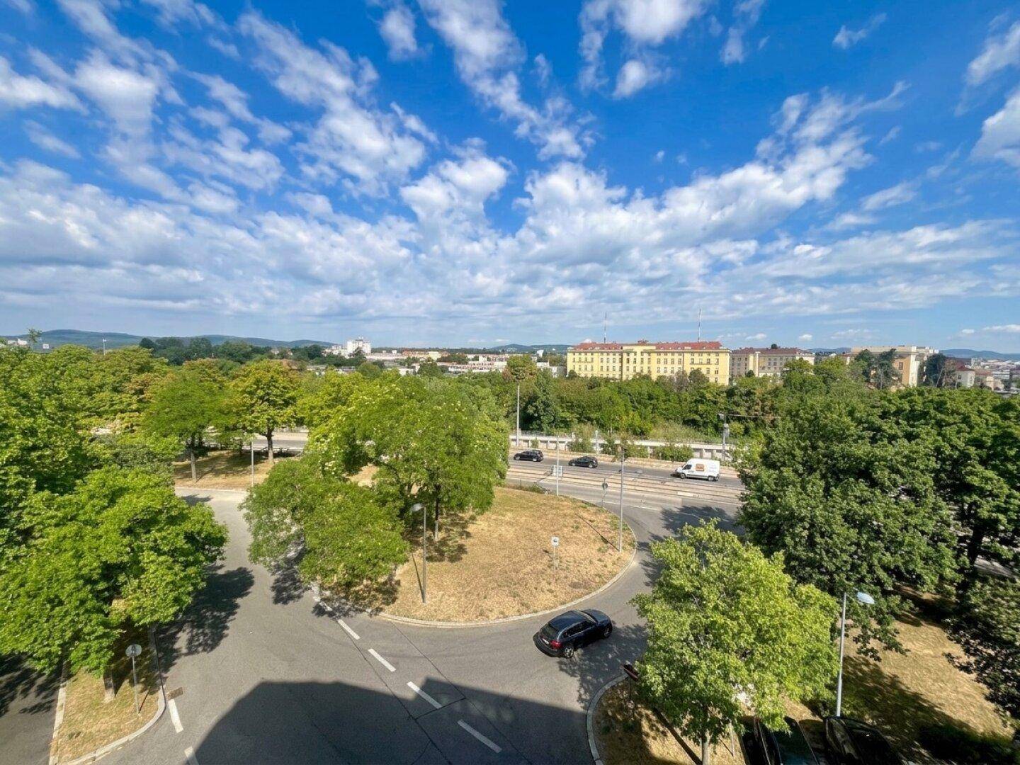 Weitläufiger Blick über die Stadt mit viel Grün und Straßenverkehr von oben.