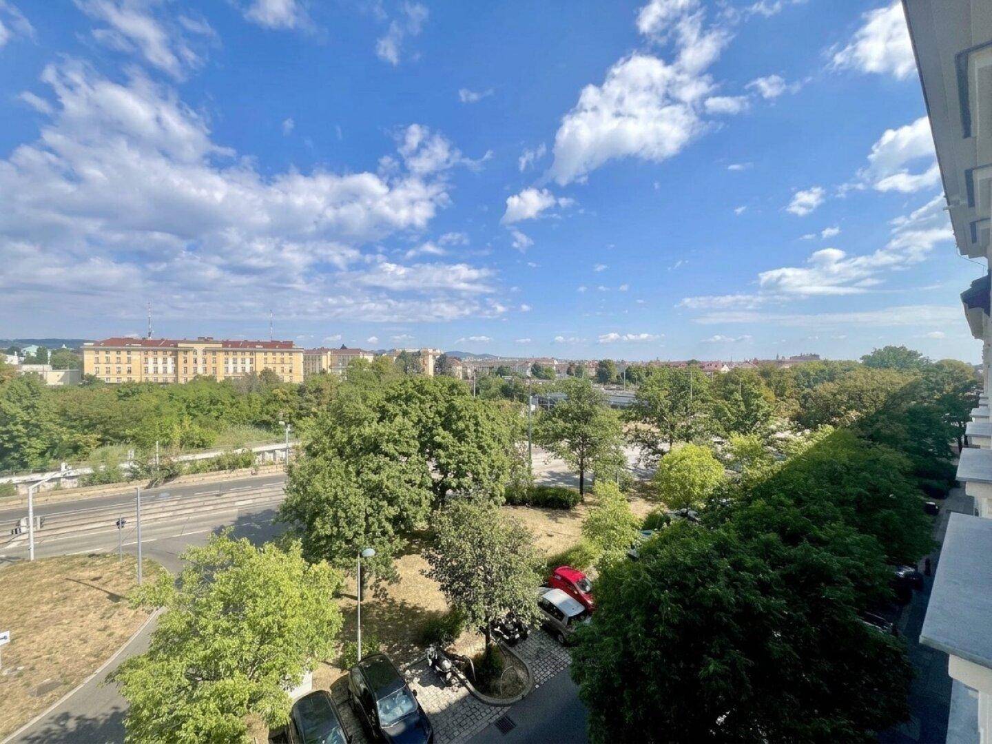 Panoramablick über die Stadt mit grünen Bäumen und Gebäuden in der Ferne an einem sonnigen Tag.
