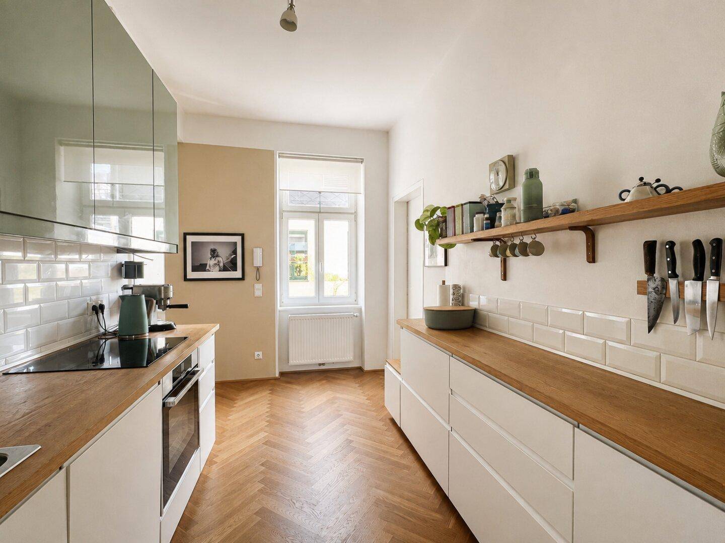 Moderne Küche mit weißen Fliesen, Holz-Arbeitsplatten und Fischgrätparkett.