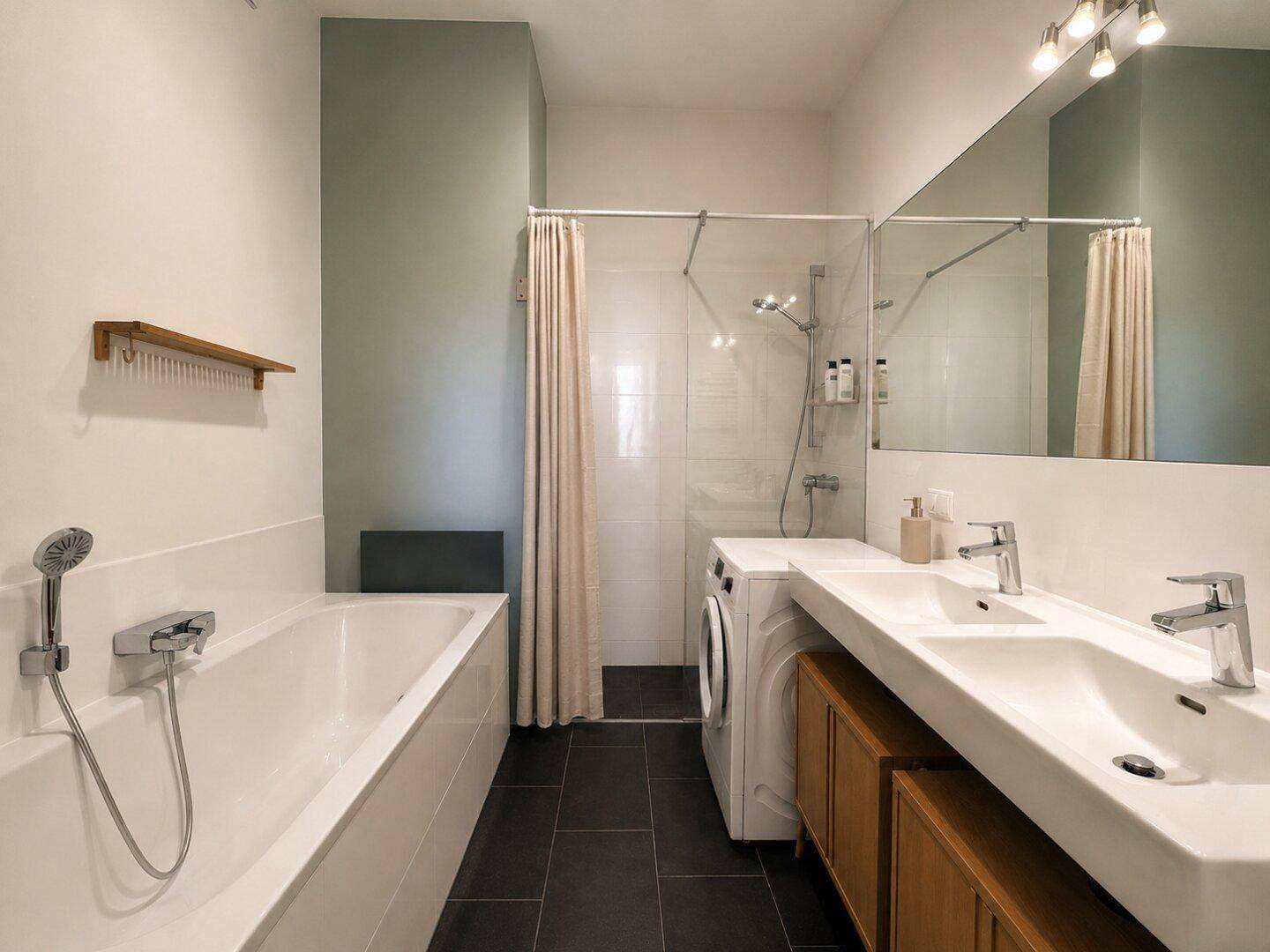 Modernes Badezimmer mit Badewanne, Dusche, Doppelwaschbecken und dunklen Fliesen.