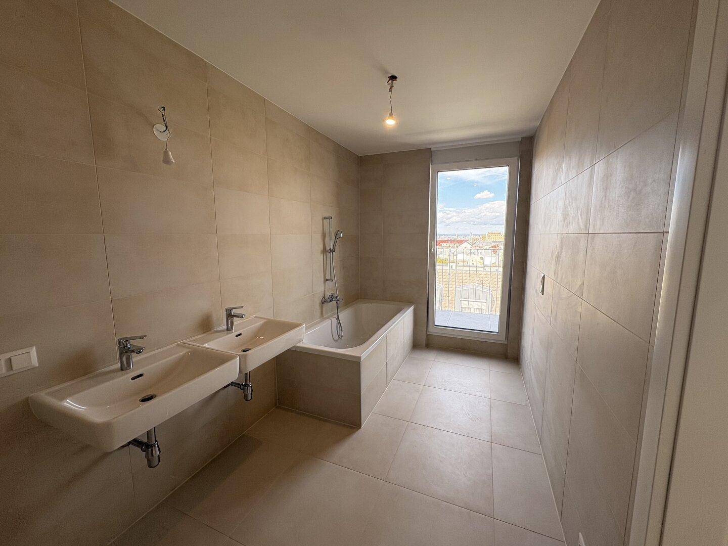 Modernes Badezimmer mit Badewanne, Doppelwaschbecken und Fenster mit Blick nach draußen.