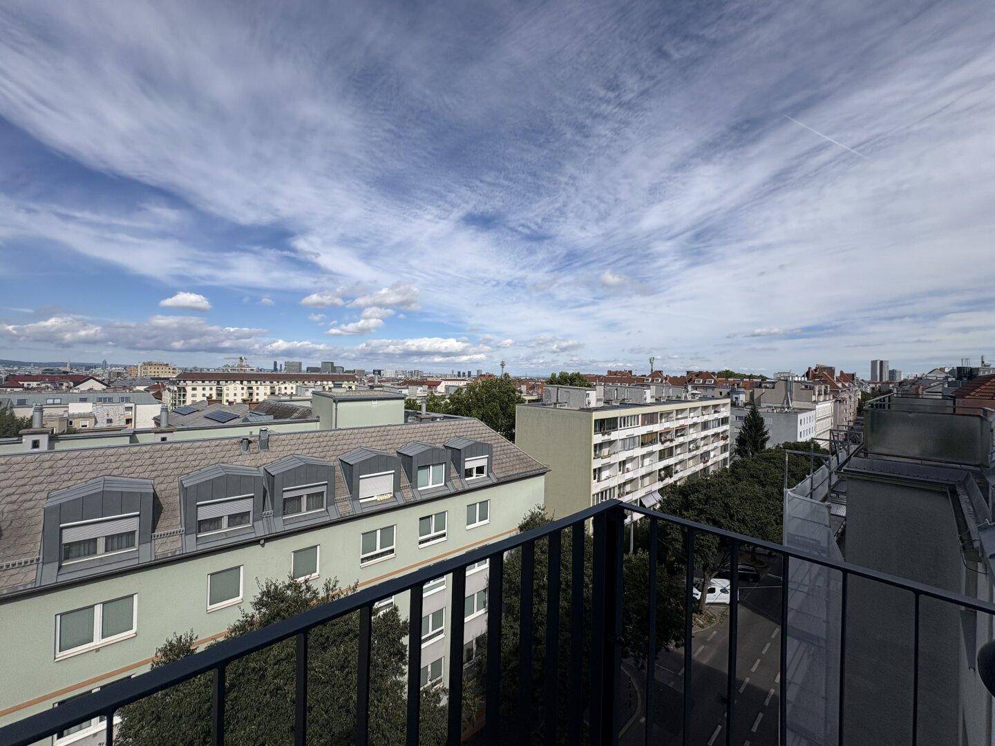 Panoramablick über die Stadt mit vielen Dächern und dem Himmel im Hintergrund.