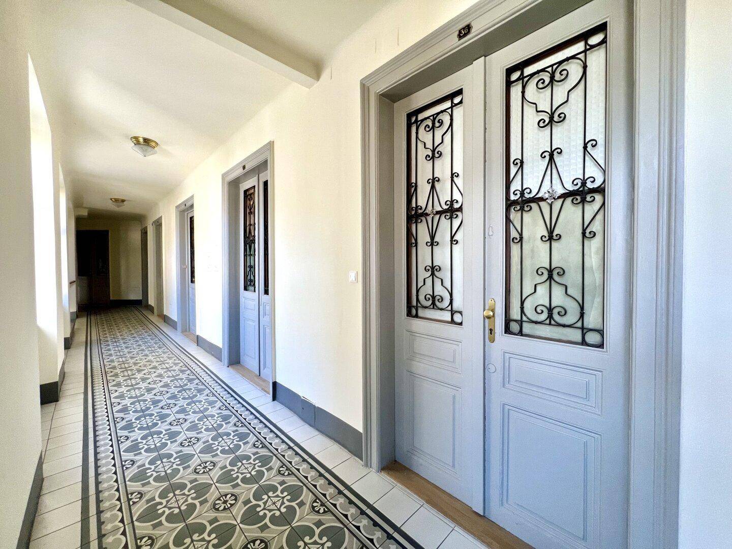 Heller Flur mit gemusterten Fliesen und eleganten Türen in einem Altbau.