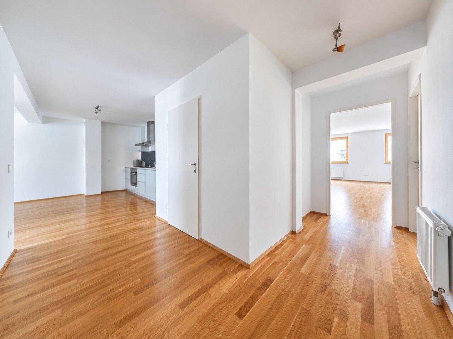 Heller Flur mit Holzparkett, der in den offenen Wohnbereich mit integrierter Küche übergeht.