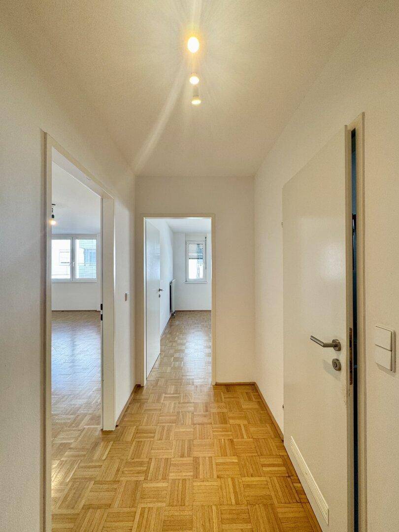 Heller Flur mit Parkettboden und mehreren Türen, der zu den verschiedenen Räumen führt.