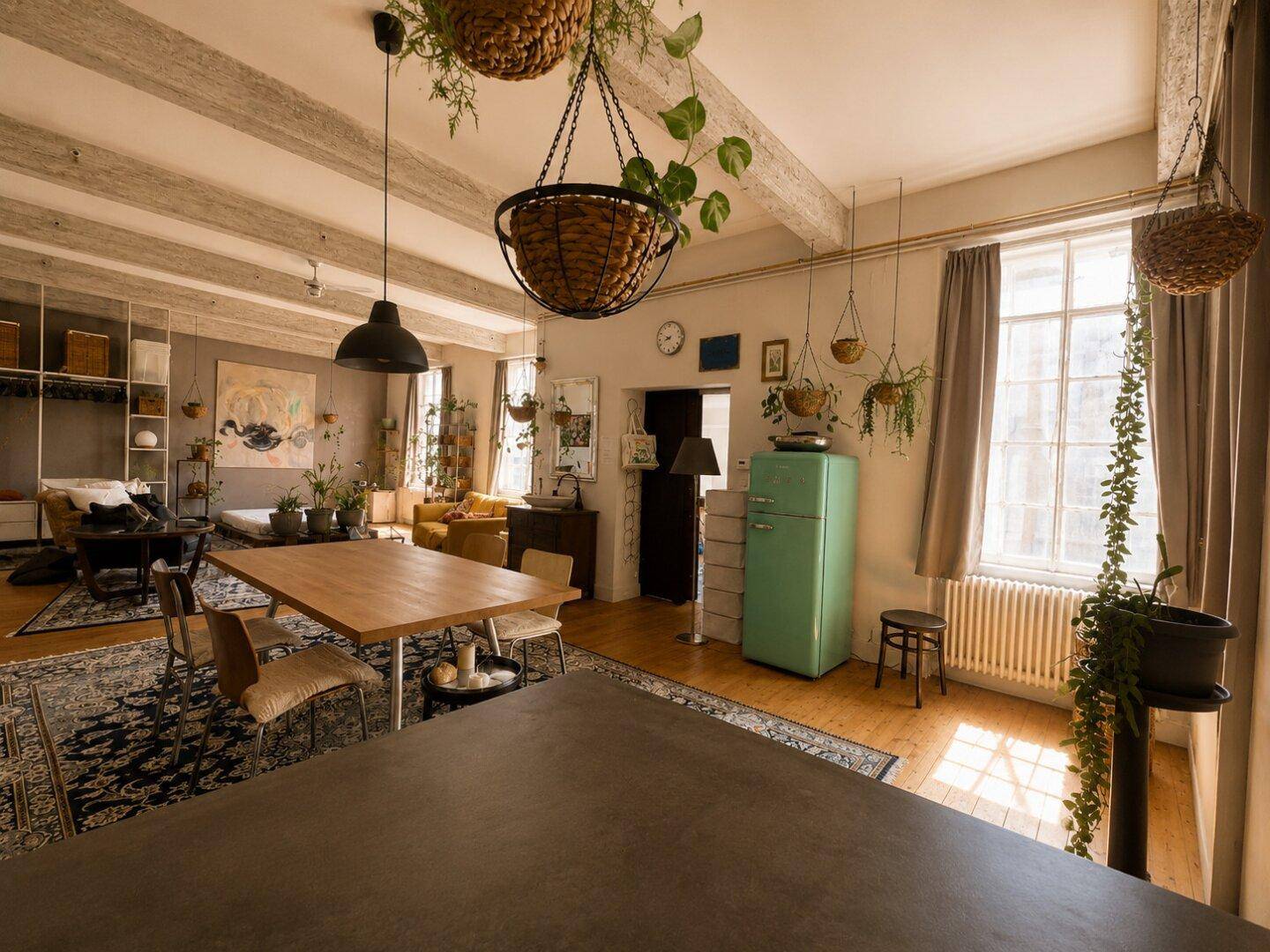 Offener Wohn-, Ess- und Küchenbereich mit hohen Decken, Holzbalken und einem auffälligen grünen Kühlschrank.