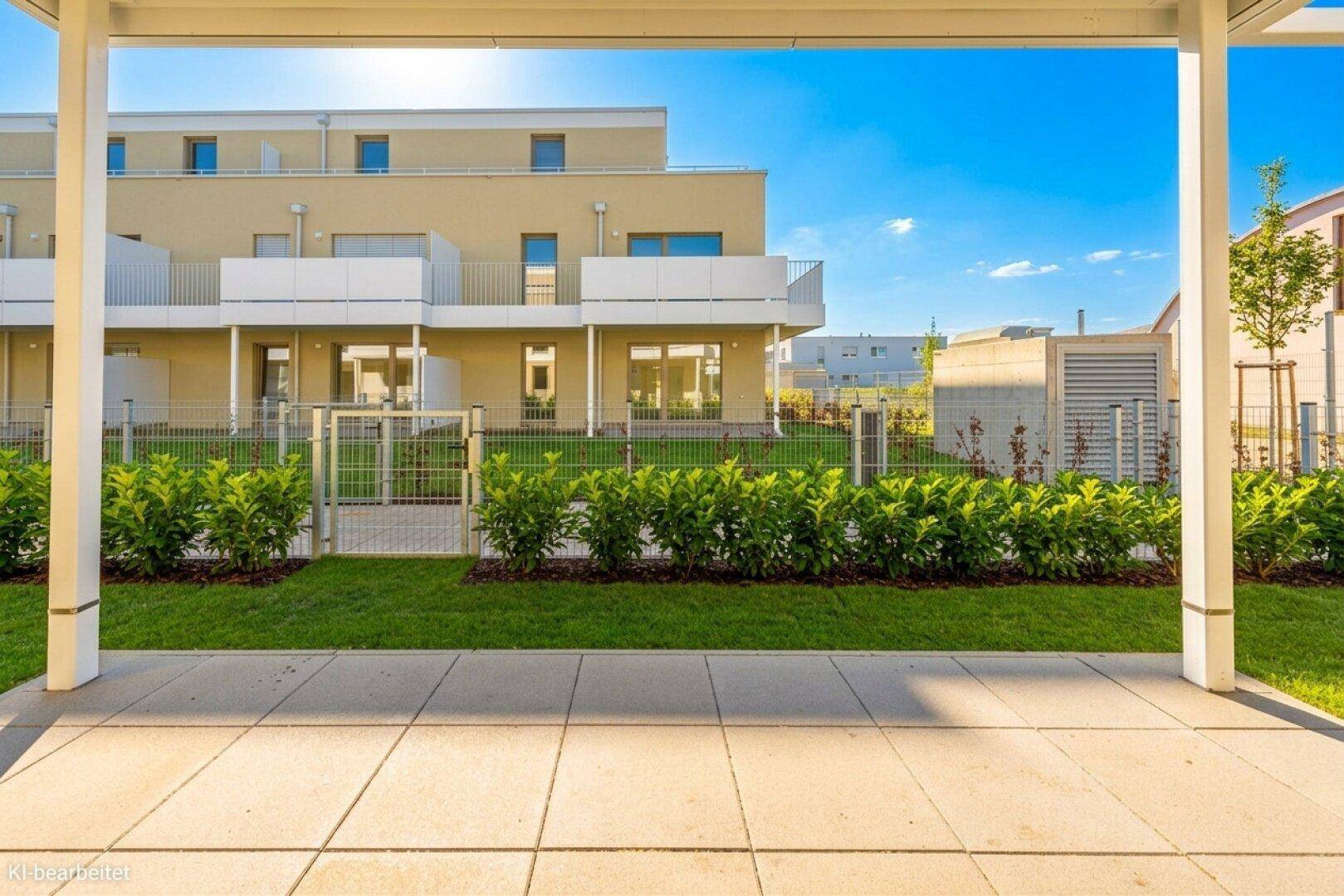 Sonniger Terrassenbereich mit Blick auf die moderne Wohnanlage und gepflegte Grünflächen.